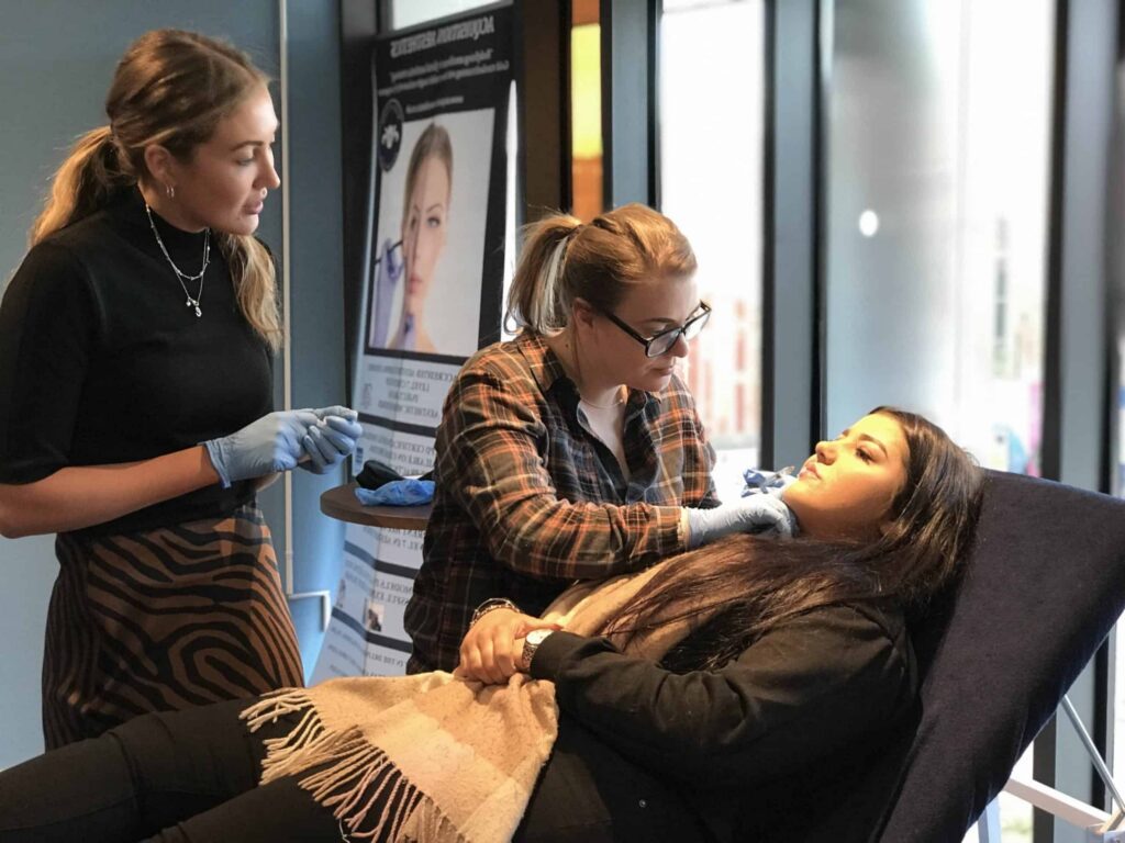 A trainer guiding a delegate through a treatment on a live patient