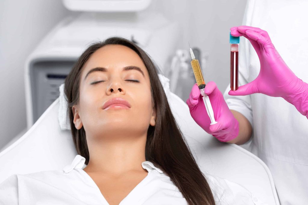 Practitioner holding a blood sample tube beside a patient in a treatment chair
