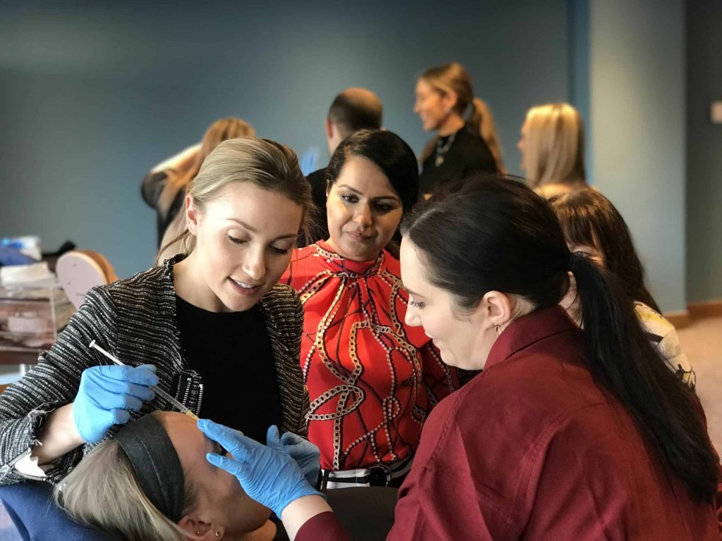 Trainer demonstrating a facial injection to delegates during a training session