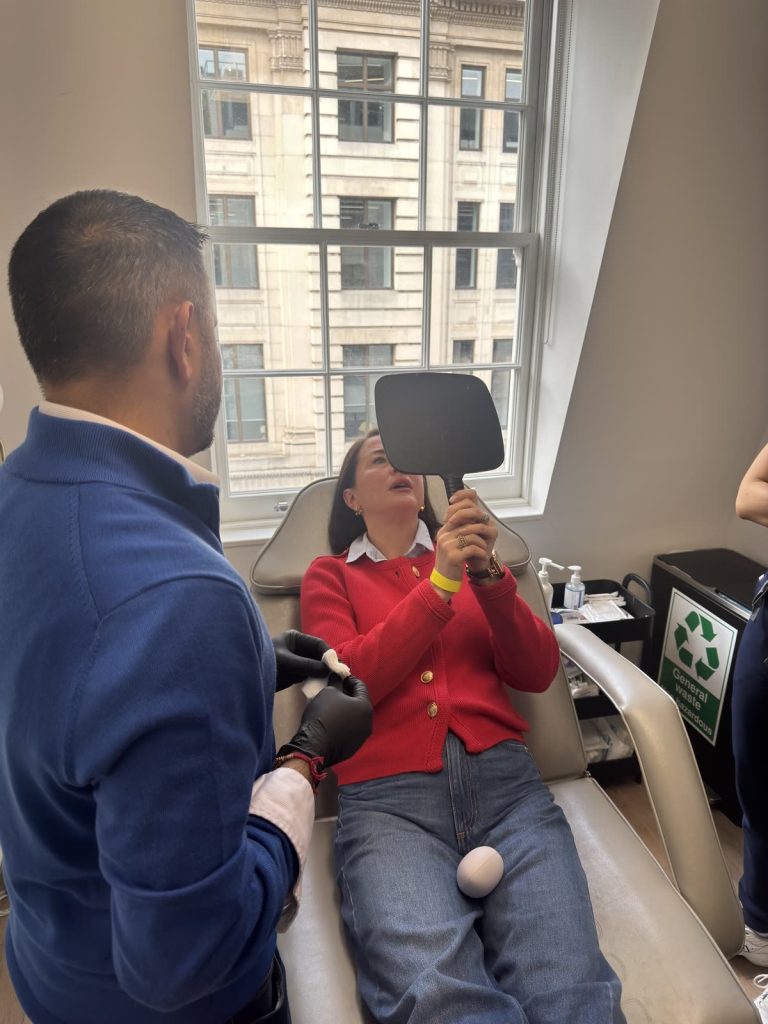 A model patient checks her result in a hand mirror during a Level 7 mentoring session.